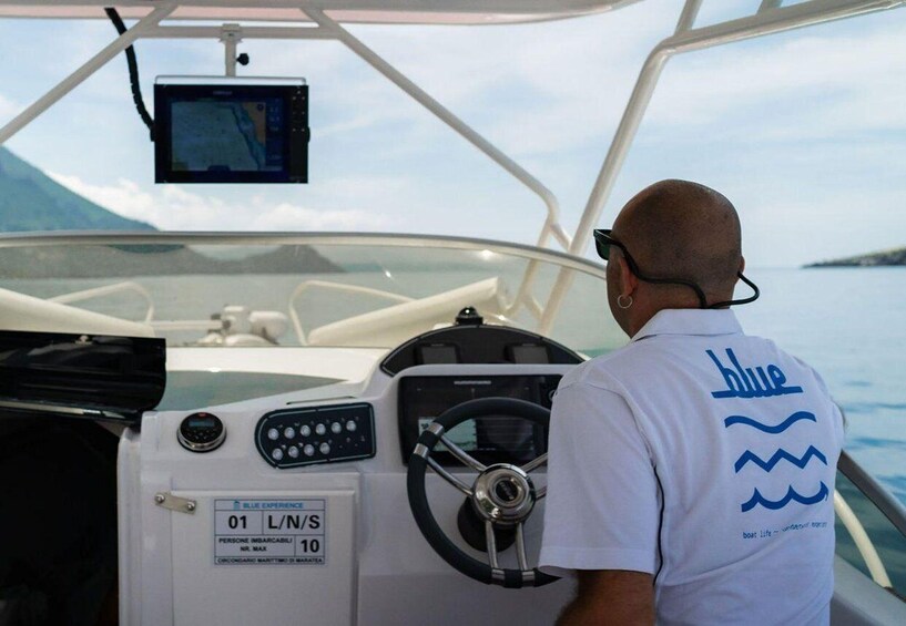 A person steering a boat with a control panel and a screen. 5