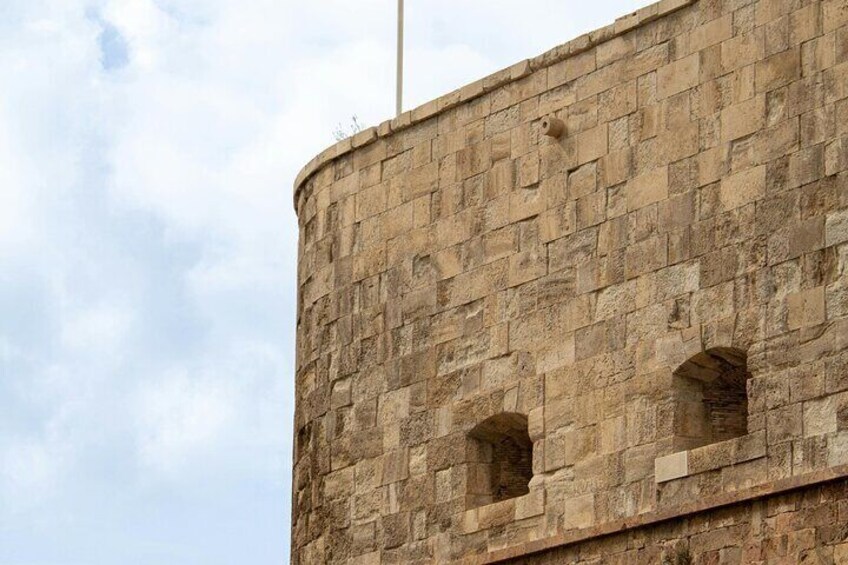 A stone wall with arched windows and a flagpole. 5