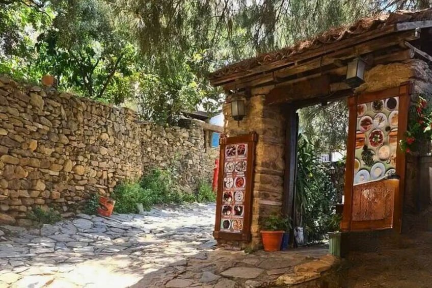 A stone wall, a rustic wooden gate, and potted plants. 5