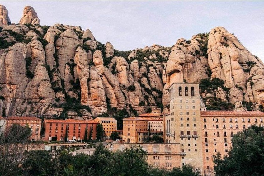 A town with buildings in front of a rocky mountain. 1