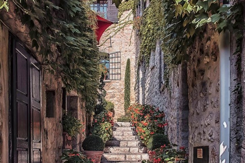 Une ruelle étroite aux murs de pierre, une porte en bois et un auvent rouge. 2