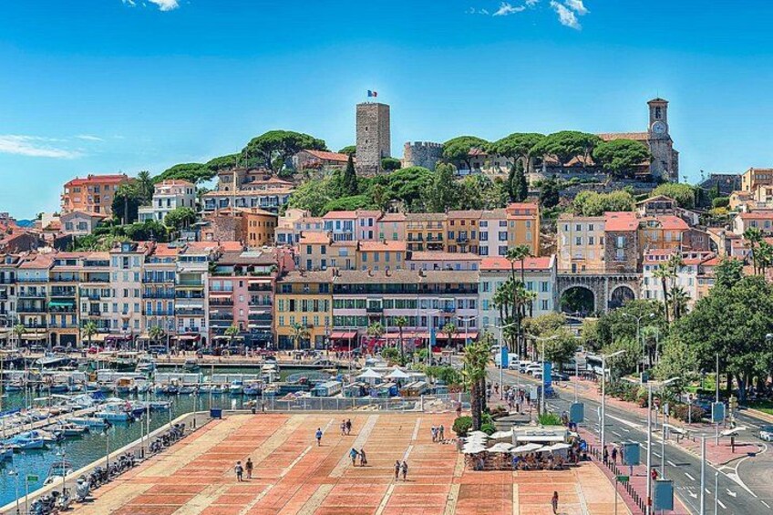 A coastal town with colorful buildings, a marina, and historic towers. 2