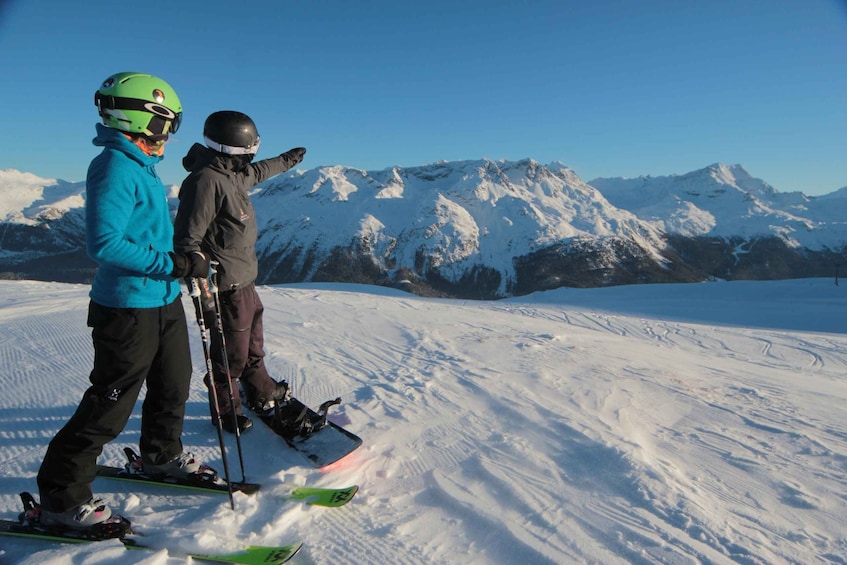Two skiers on a snowy slope with a mountain range in the background. 2