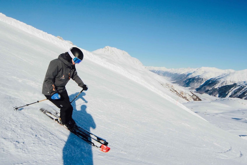 A skier on a snowy slope with mountains in the background. 1