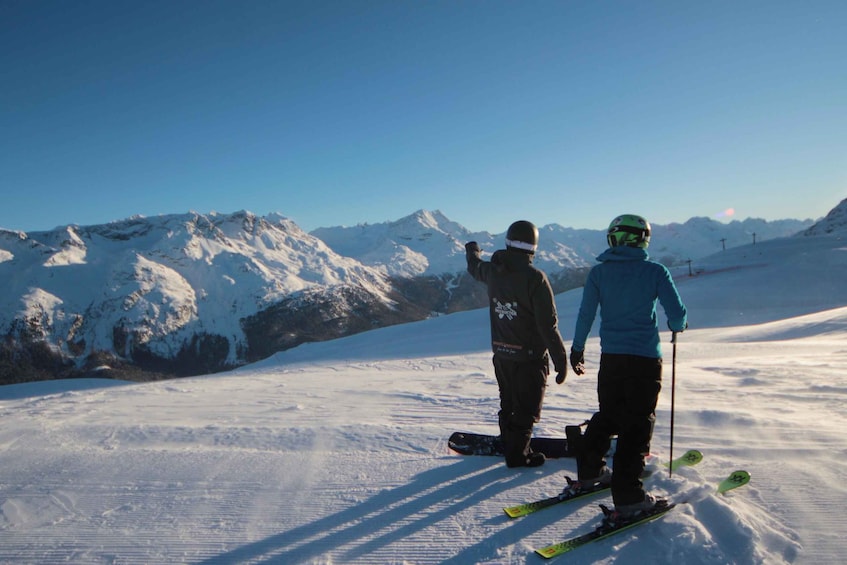 Two skiers on a snowy slope with a mountain range in the background. 3