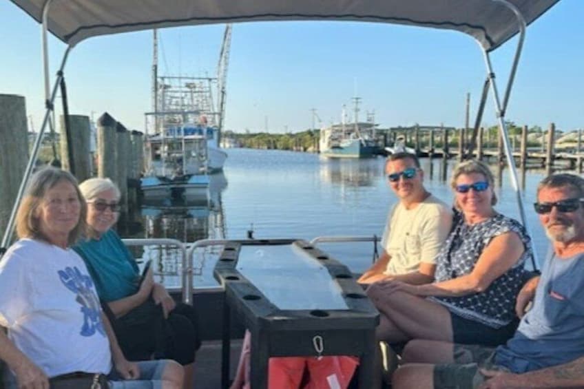 A group of people on a boat with a dock and waterway in the background. 2