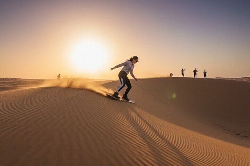 Une personne faisant de la planche à sable sur une dune, avec le soleil couchant en arrière-plan. 5