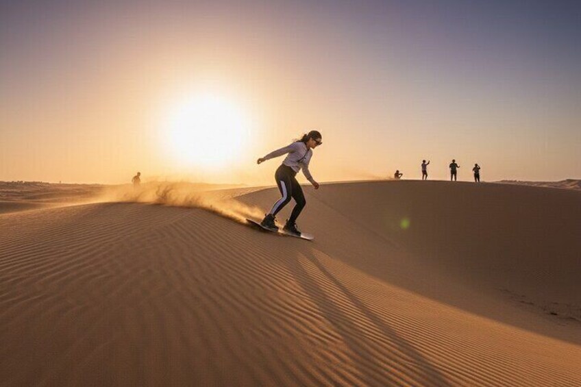 Une personne faisant de la planche à sable sur une dune au coucher du soleil. 3