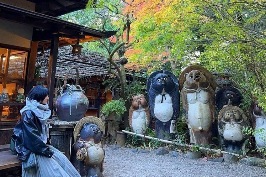 A person sitting on a bench in a garden with large ceramic animal figures and traditional Japanese architecture in the background. 4