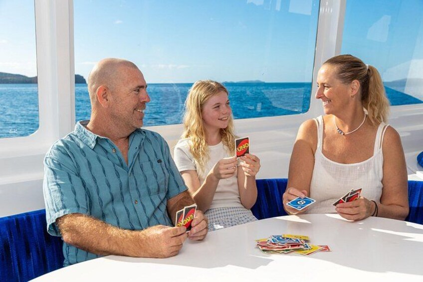 En familie spiller UNO på en båd med udsigt over havet. 3