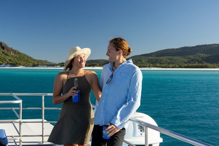 Dos personas en un bote con un mar azul cristalino y un paisaje montañoso al fondo. 4