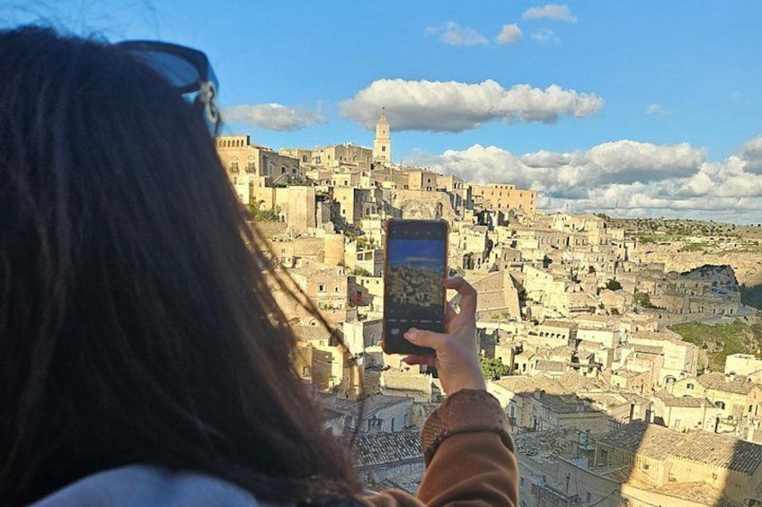 A person taking a photo of a historic cityscape with a prominent tower. 3
