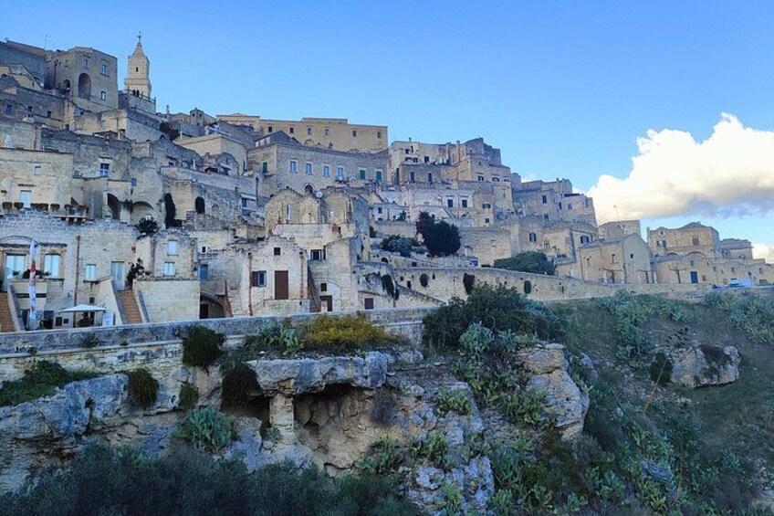 A historic town with stone buildings, a prominent church, and a rocky foreground. 5