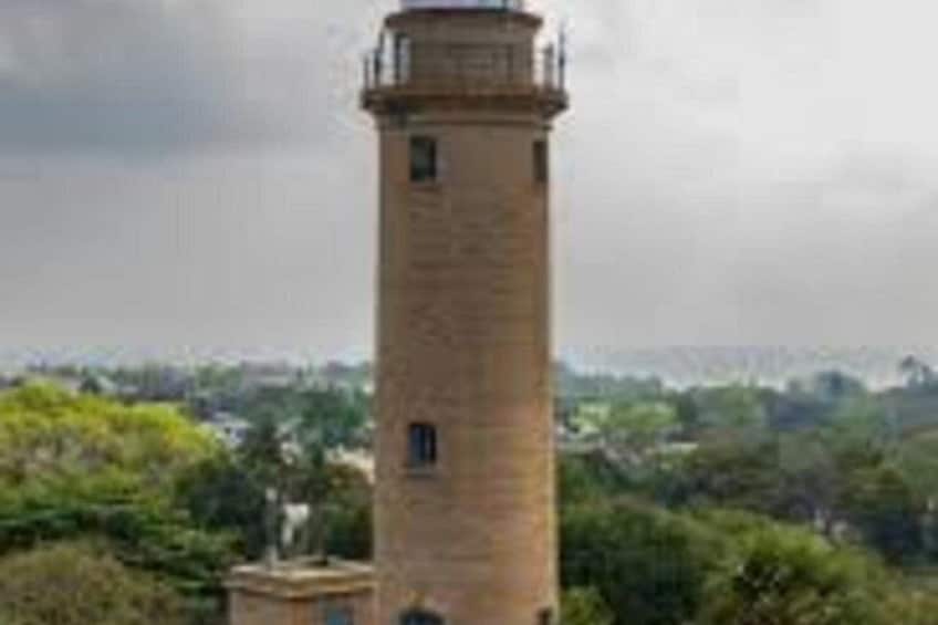 Una torre alta y cilíndrica con balcón, rodeada de abundante vegetación y un cielo nublado. 4