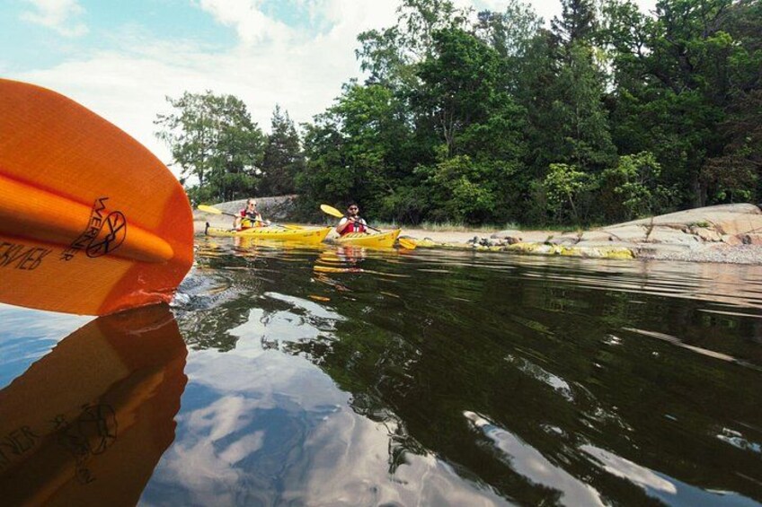 A river with kayaks, a surfboard, and a forested area. 2