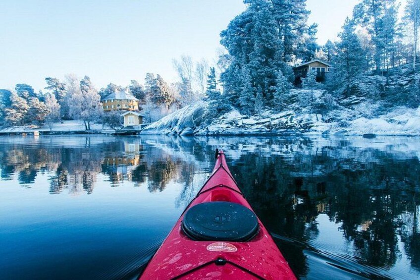 A red kayak on calm water with reflections of trees and houses. 1