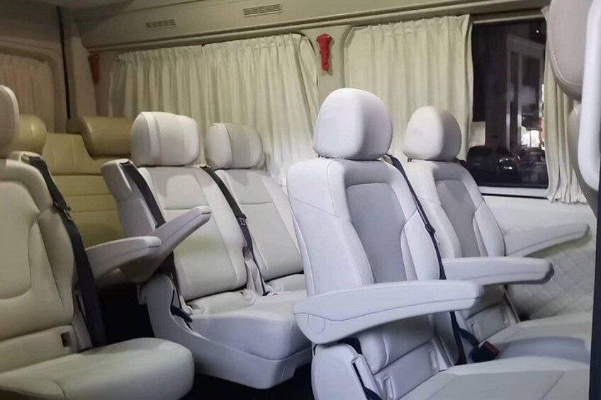 A row of white leather seats with headrests and armrests in a vehicle. 5