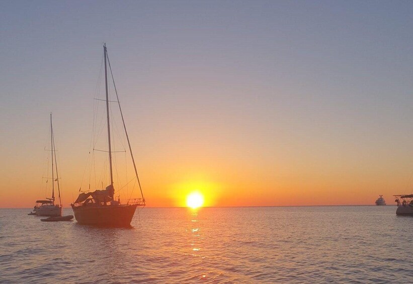 A sunset over calm waters with sailboats and a yacht. 5