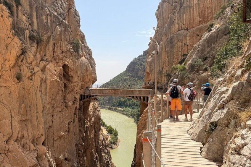 Un puente de madera cruzando un cañón, con excursionistas. 4