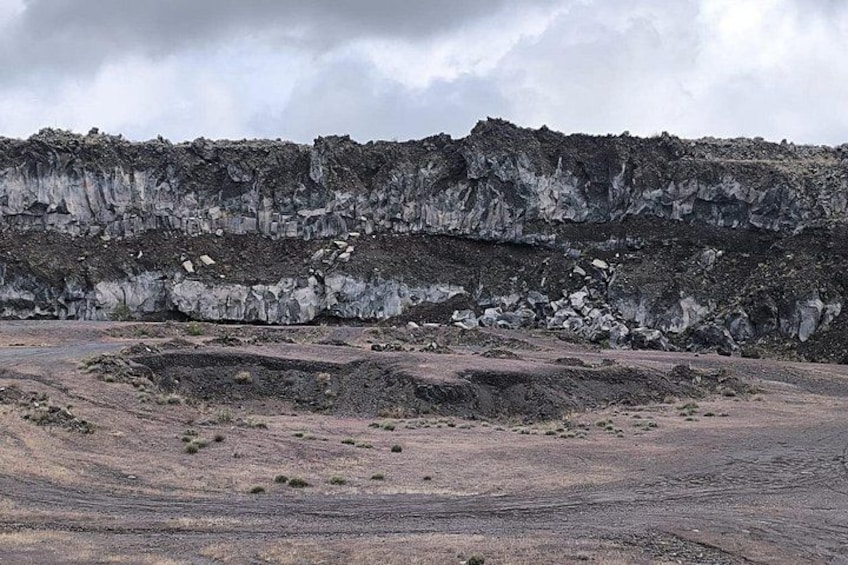 A barren landscape with layered rock formations and a cloudy sky. 4