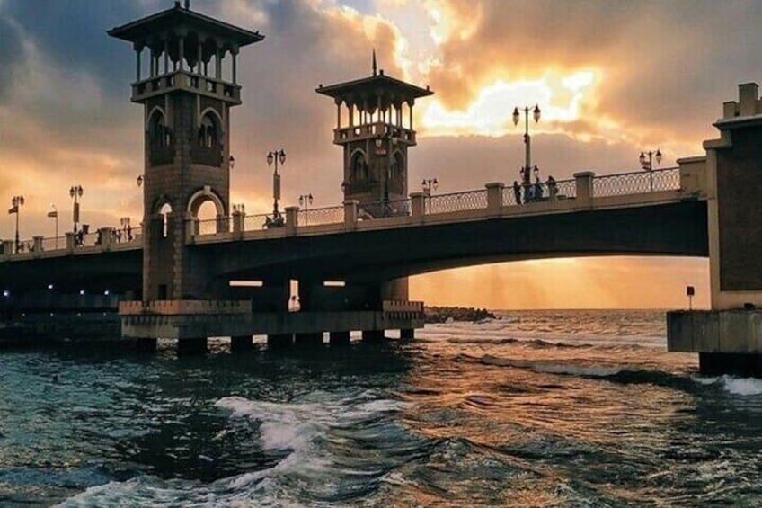 A bridge with two towers, a sunset, and waves. 1