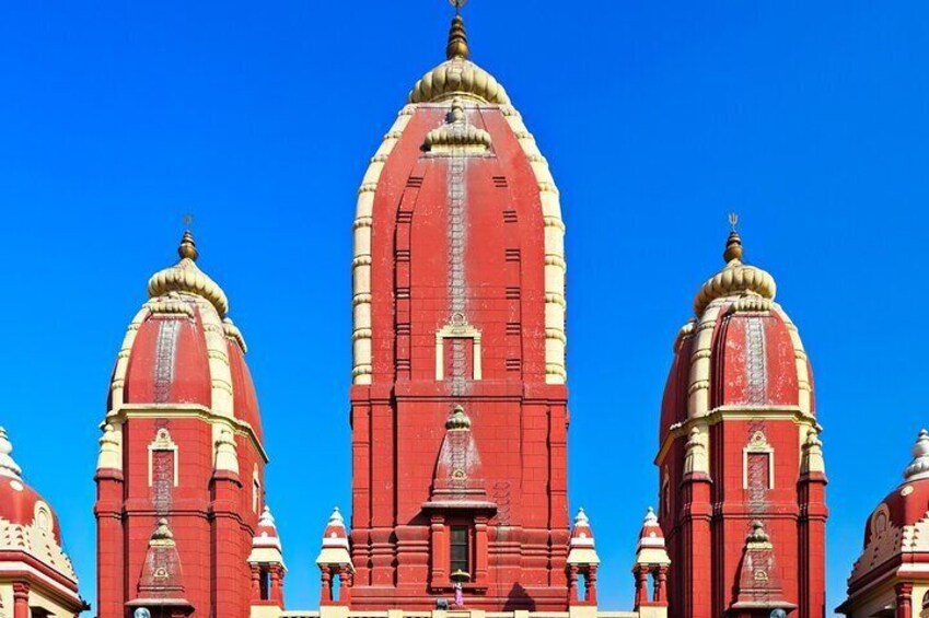 Un templo rojo grande con múltiples cúpulas y agujas, frente a un cielo azul despejado. 2