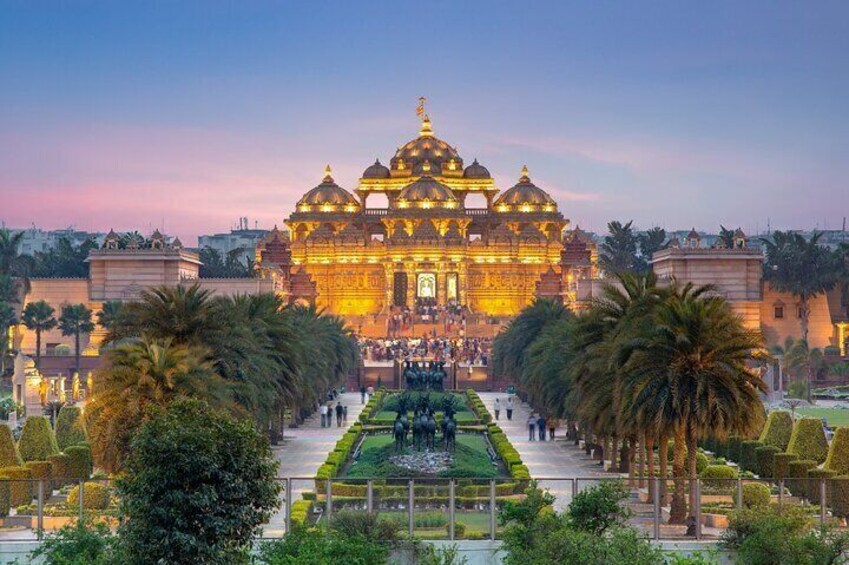 Un templo grande y ornamentado con varias cúpulas, rodeado de jardines cuidados y palmeras. 1