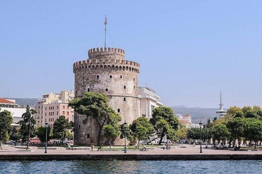 A historic stone tower with a round tower, surrounded by trees and a body of water. 4