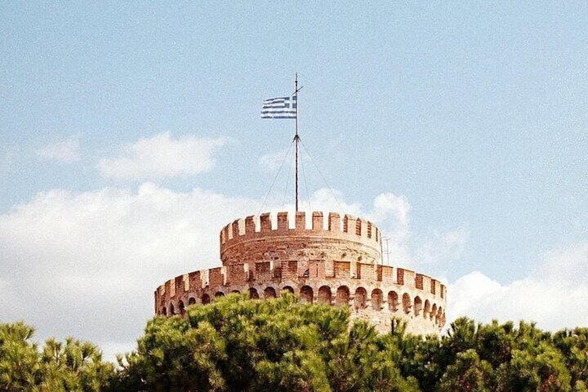 A historic circular fortress with a flag on top, surrounded by greenery. 2