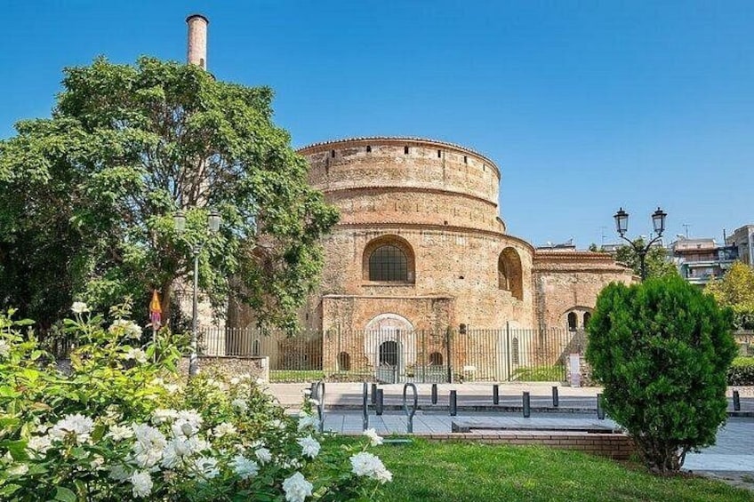 A historic building with a round tower, surrounded by well-maintained gardens and a clear blue sky. 5