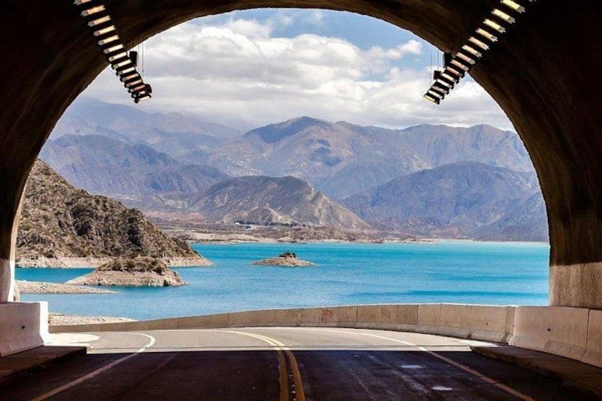 A tunnel with a view of mountains and a lake. 1