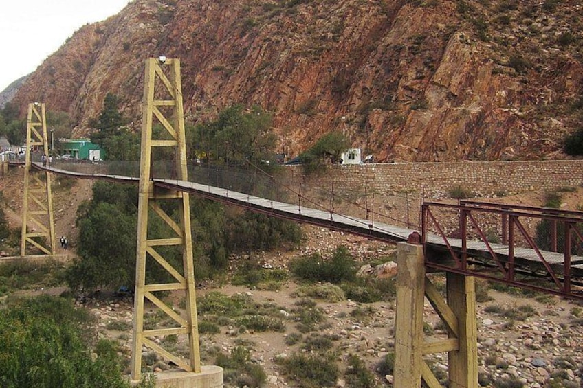 A bridge with yellow supports, a river, and a rocky hillside in the background. 4