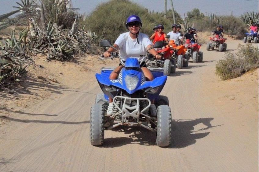 Un groupe de personnes conduisant des quads sur un chemin de terre, entouré de végétation. 5