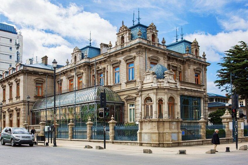 A historic building with ornate architecture, a glass conservatory, and a blue roof. 2