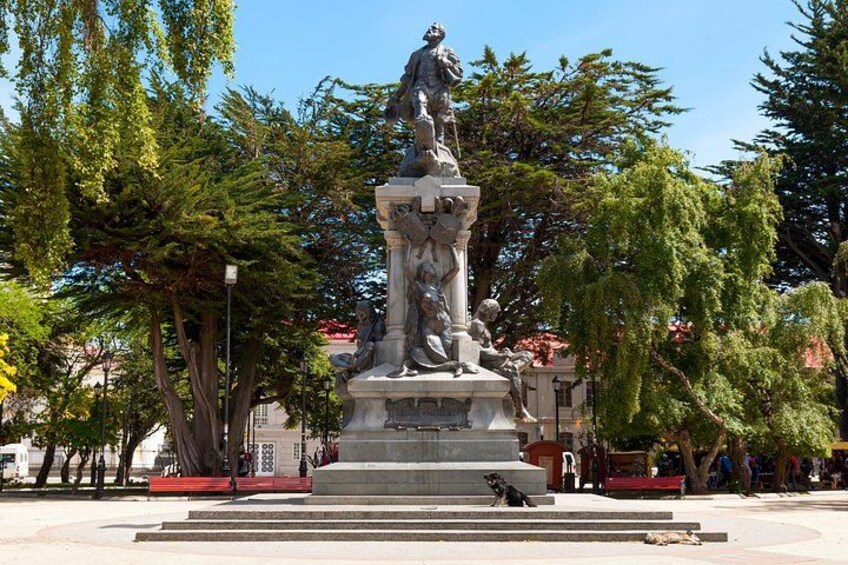A statue in a park with steps leading up to it, surrounded by trees and a clear sky. 1
