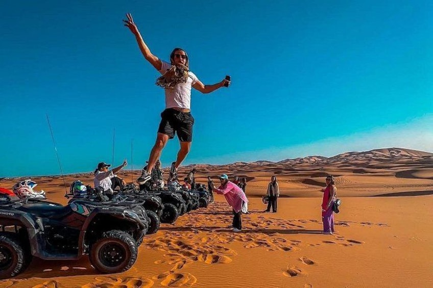 Une personne se tient sur une rangée de quads dans un désert, avec des dunes de sable en arrière-plan. 4