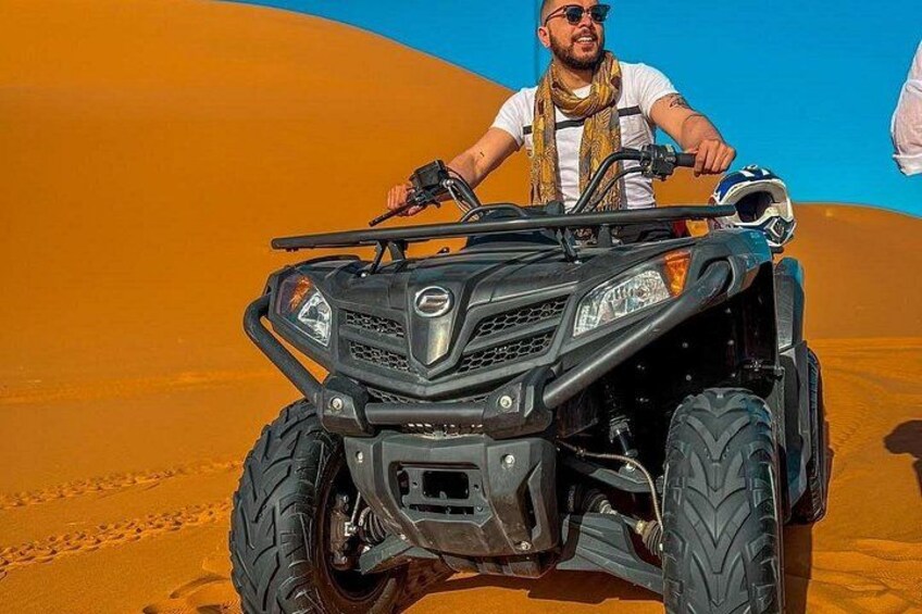 Une personne conduisant un quad dans un désert de dunes de sable. 3