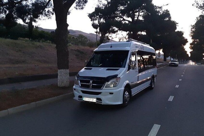 A white van parked on a road with trees on the side. 3