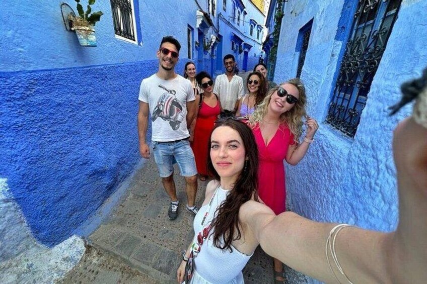 A group of people in a narrow alley with blue walls. 5