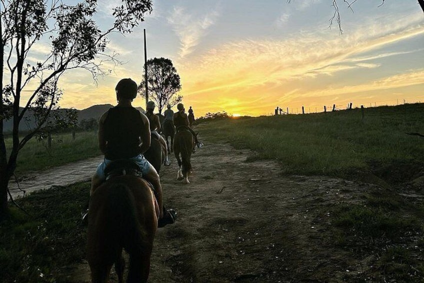 Un chemin de terre où l’on voit des personnes à cheval, se dirigeant vers le soleil couchant. 2