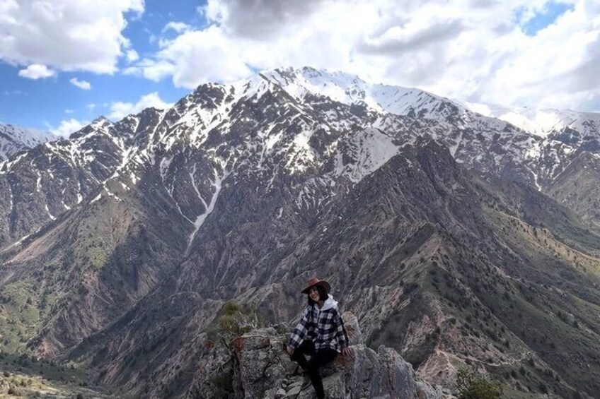 Une personne se tient debout sur un promontoire rocheux, avec des montagnes enneigées en arrière-plan. 4