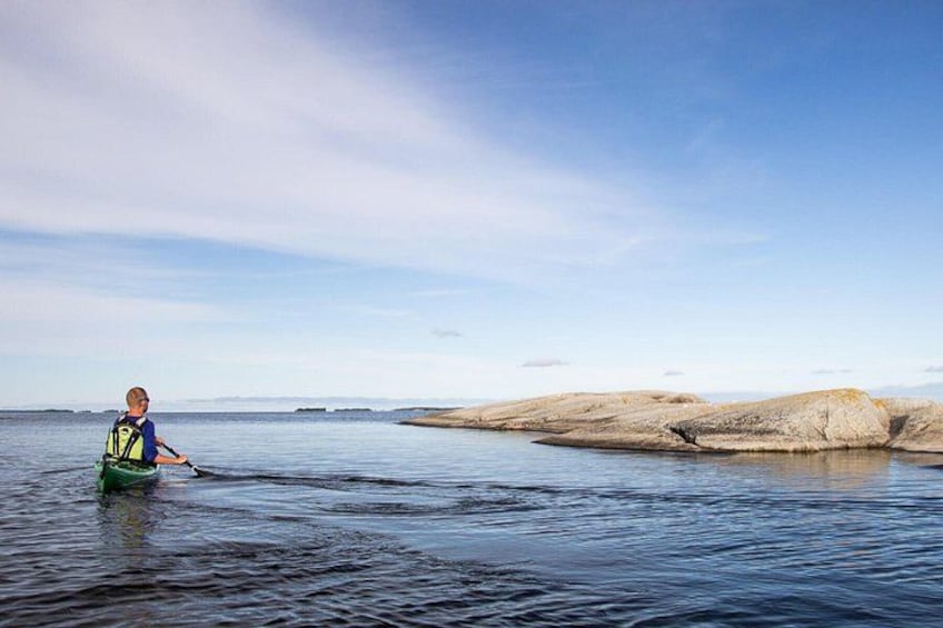 A person kayaking on calm water with distant rocky formations. 2