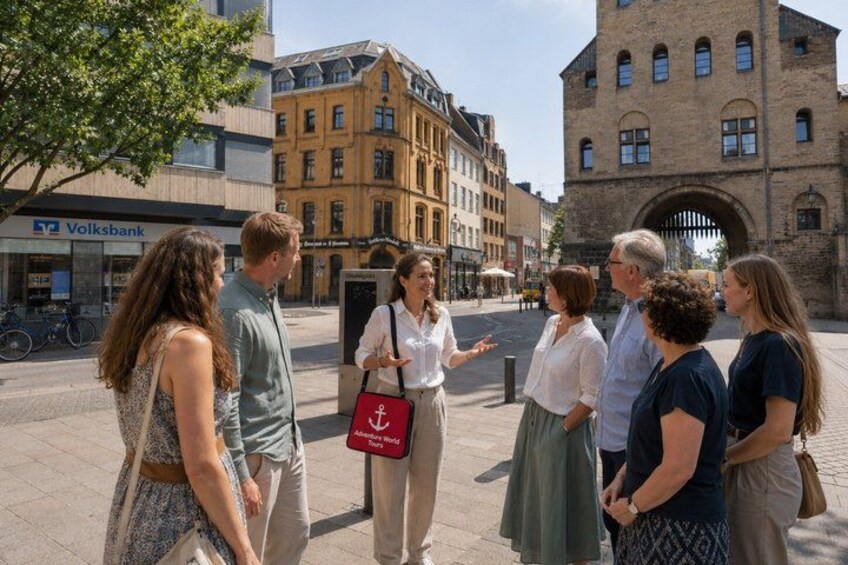 A group of people standing on a city street with historic buildings and a bank in the background. 2