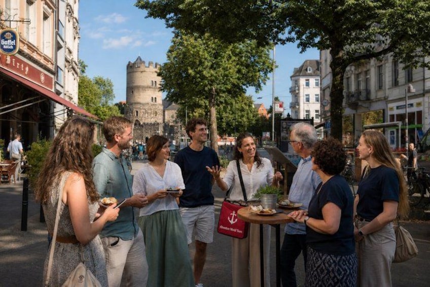 A group of people standing around a table with food, a castle in the background, and a coffee shop sign. 3