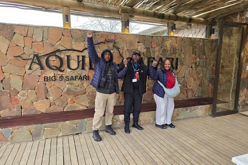 A group of people standing in front of a stone wall with the text 'AQUARI BIG 5 SAFARI'. 3