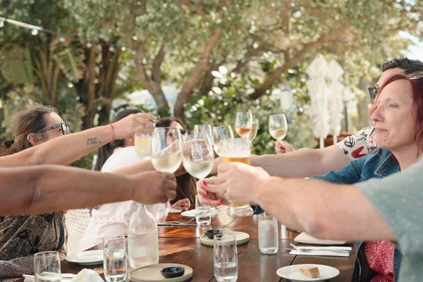 A group of people toasting with wine glasses at an outdoor table. 2