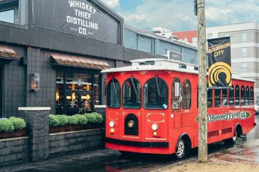 A red bus parked in front of a building with a sign that reads 'Whiskey Thief Distilling Co.' 3
