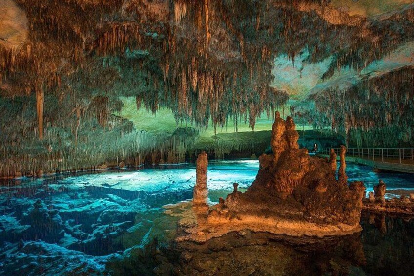 Una cueva con estalactitas, un charco de agua y un saliente rocoso. 5