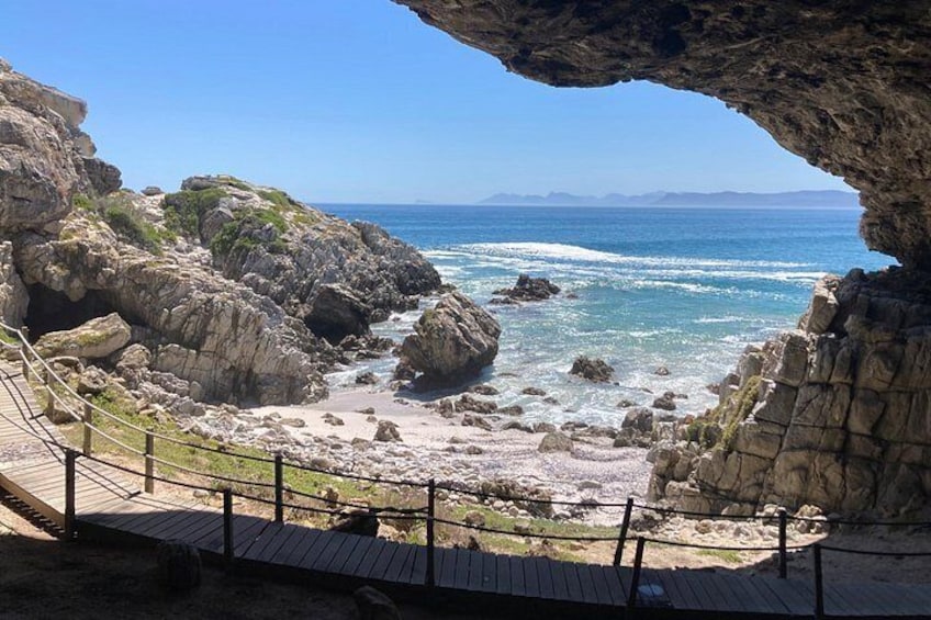A rocky coastal landscape with a wooden walkway and a natural cave entrance. 3