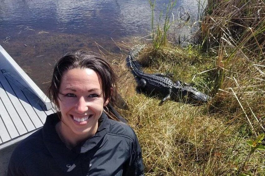 A person standing near a dock with an alligator in the background. 1